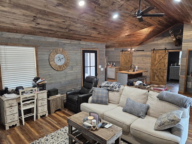 living room featuring lofted ceiling, wood ceiling, dark wood-type flooring, wooden walls, and a barn door