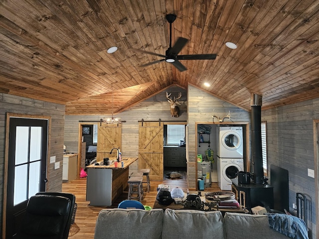 living room featuring wood ceiling, wooden walls, stacked washer and clothes dryer, and vaulted ceiling