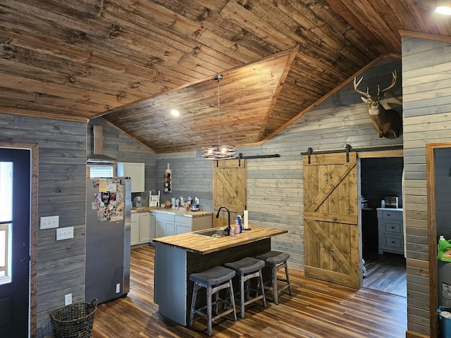 kitchen with sink, wood ceiling, stainless steel fridge, white cabinetry, and a barn door