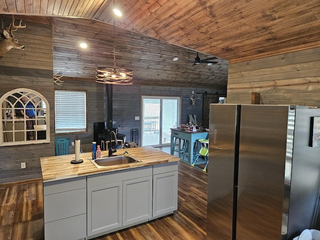 kitchen featuring wooden walls, sink, wooden counters, stainless steel fridge, and wood ceiling