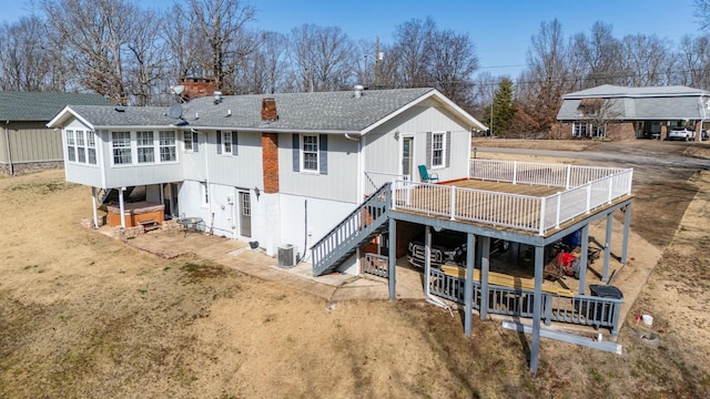 back of house with central AC unit, a sunroom, a covered hot tub, a wooden deck, and a patio