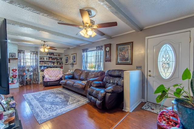 living room with built in shelves, a textured ceiling, ceiling fan, beam ceiling, and hardwood / wood-style floors