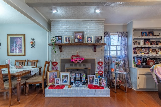 interior space featuring a brick fireplace, wood-type flooring, ornamental molding, and a textured ceiling