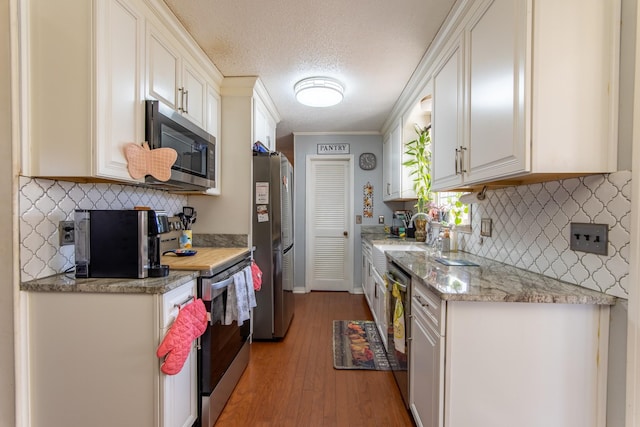 kitchen featuring sink, white cabinetry, a textured ceiling, light hardwood / wood-style flooring, and appliances with stainless steel finishes