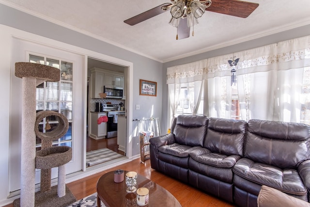 living room with ceiling fan, ornamental molding, light hardwood / wood-style flooring, and a textured ceiling