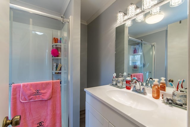 bathroom with ornamental molding, vanity, and a shower with shower door