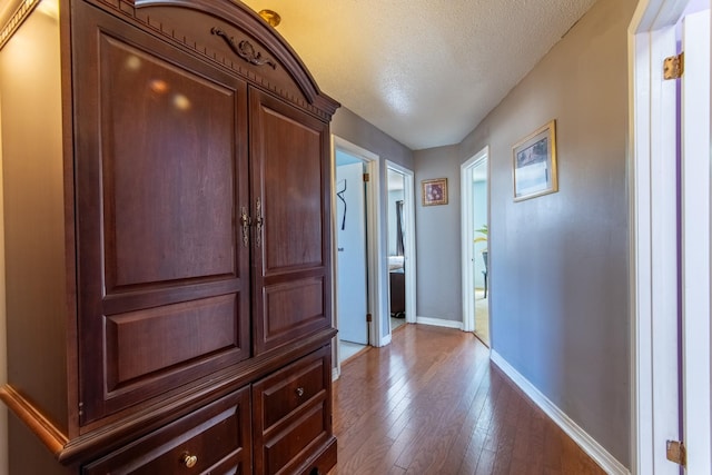 corridor featuring wood-type flooring and a textured ceiling