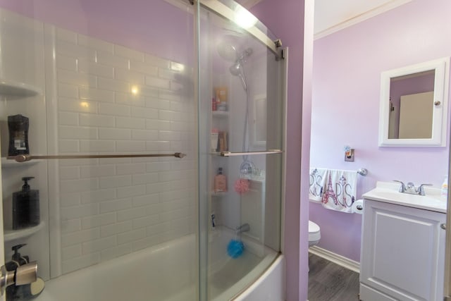 full bathroom featuring shower / bath combination with glass door, hardwood / wood-style flooring, vanity, toilet, and crown molding