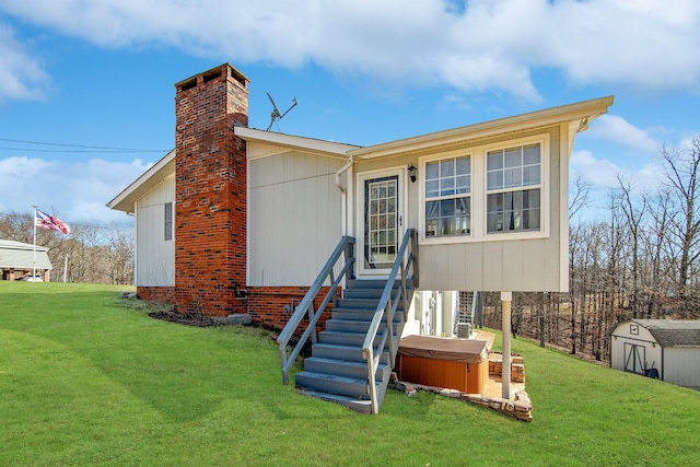 back of house with a shed, a lawn, and a hot tub