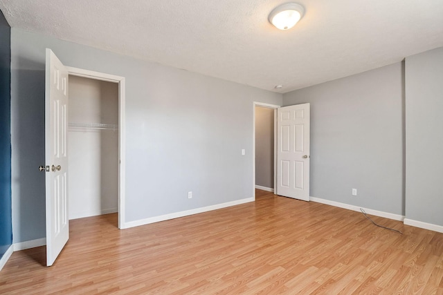 unfurnished bedroom featuring a textured ceiling, light wood-type flooring, and a closet