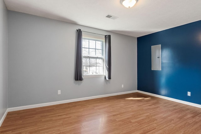 unfurnished room featuring electric panel and light hardwood / wood-style floors