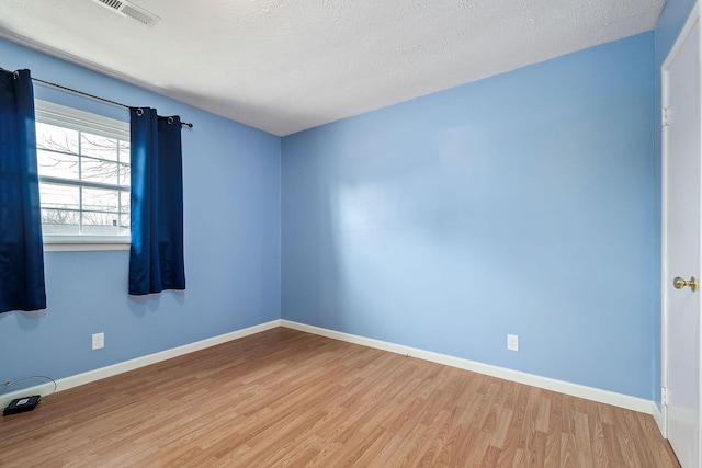 empty room with a textured ceiling and light hardwood / wood-style floors