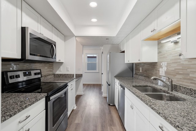 kitchen featuring stainless steel appliances, sink, dark stone countertops, and white cabinets