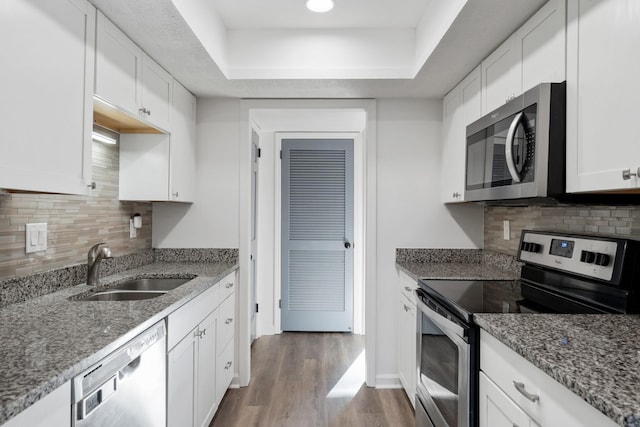 kitchen featuring sink, dark wood-type flooring, white cabinetry, stainless steel appliances, and dark stone counters