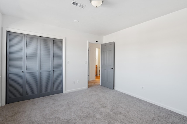 unfurnished bedroom featuring light colored carpet and a closet