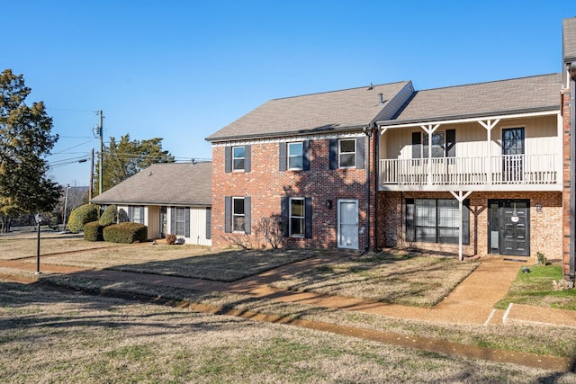 view of front facade featuring a balcony and a front yard