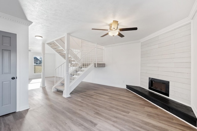 unfurnished living room with ornamental molding, hardwood / wood-style floors, a textured ceiling, and ceiling fan