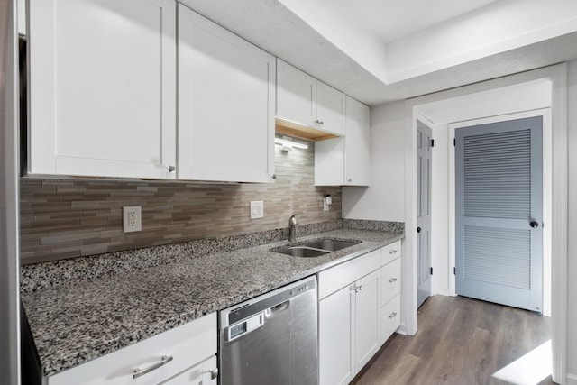 kitchen featuring sink, dishwasher, white cabinetry, backsplash, and dark stone counters