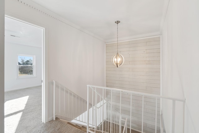 corridor with an inviting chandelier, carpet floors, and ornamental molding