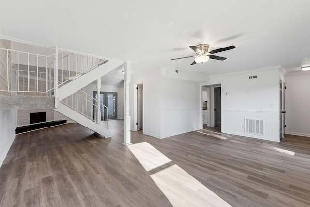 unfurnished living room with decorative columns, ornamental molding, wood-type flooring, and ceiling fan