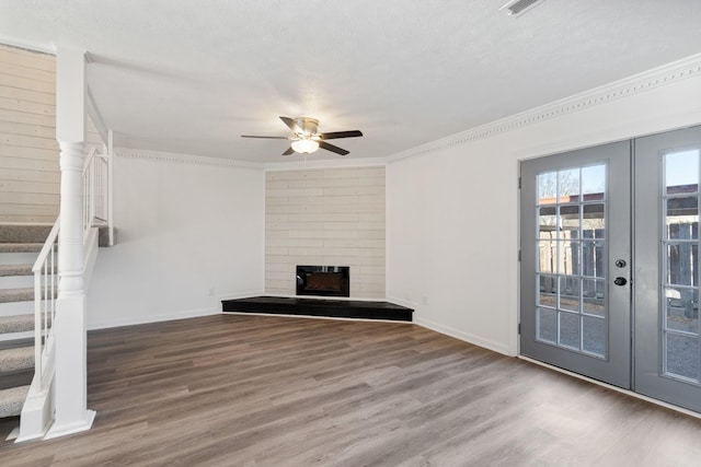 unfurnished living room with hardwood / wood-style flooring, crown molding, a fireplace, and french doors