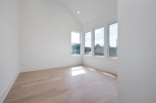 spare room with high vaulted ceiling and light wood-type flooring