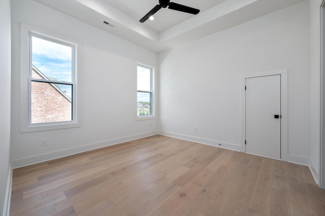 unfurnished room with ceiling fan, a raised ceiling, and light wood-type flooring