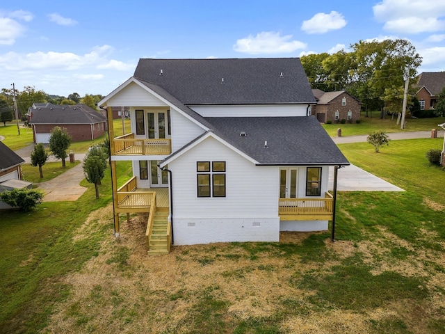 back of house with a balcony, a lawn, and french doors
