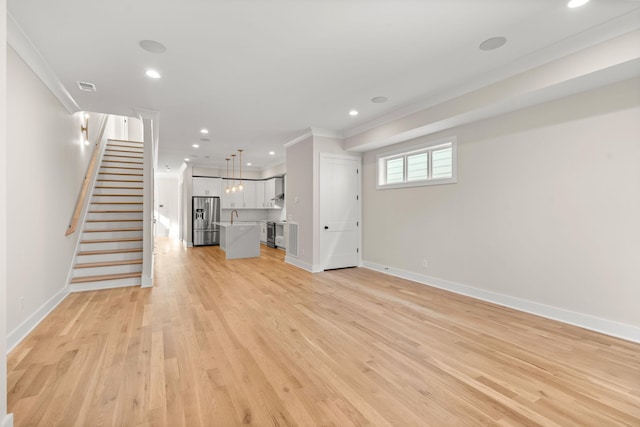 unfurnished living room with crown molding, sink, and light hardwood / wood-style floors