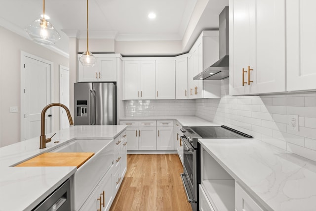 kitchen with pendant lighting, tasteful backsplash, white cabinetry, stainless steel appliances, and wall chimney exhaust hood