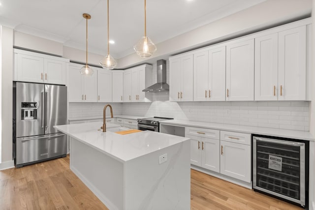 kitchen featuring wall chimney exhaust hood, white cabinetry, decorative light fixtures, stainless steel appliances, and beverage cooler