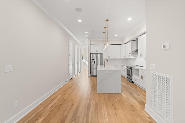 kitchen featuring sink, white cabinetry, decorative light fixtures, an island with sink, and stainless steel appliances