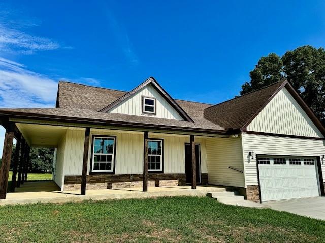 view of front of home featuring a garage, covered porch, and a front lawn