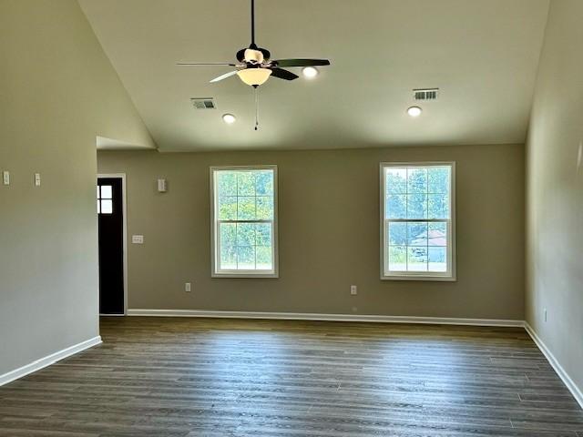 spare room featuring ceiling fan, plenty of natural light, dark hardwood / wood-style floors, and vaulted ceiling