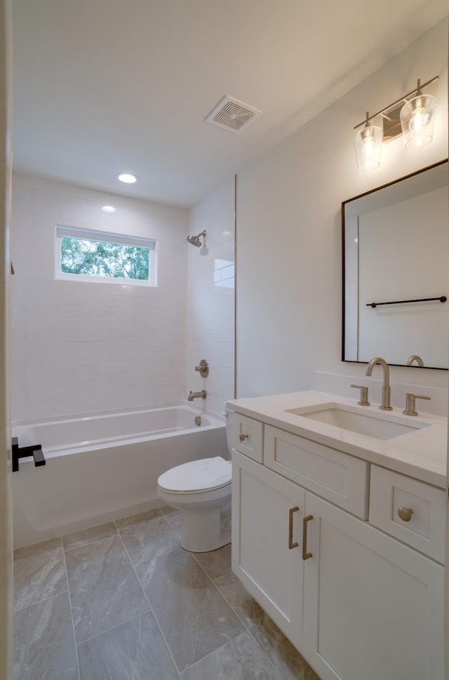 full bathroom featuring vanity, tiled shower / bath, and toilet