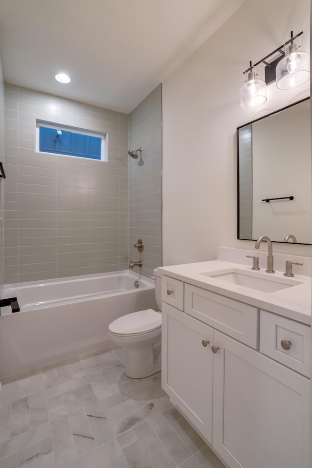 full bathroom featuring tiled shower / bath, vanity, and toilet