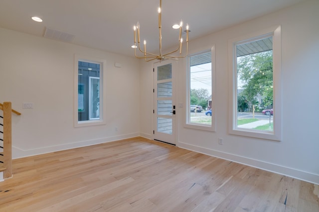 unfurnished dining area featuring an inviting chandelier and light hardwood / wood-style floors