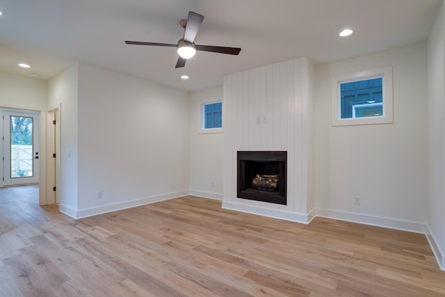 unfurnished living room featuring ceiling fan, a large fireplace, and light hardwood / wood-style floors