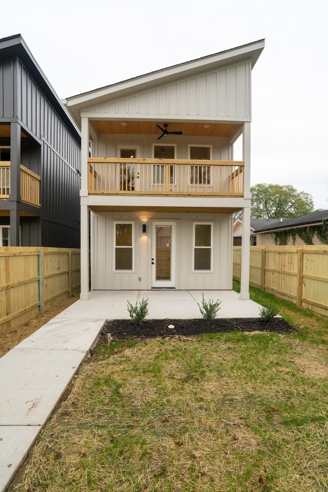 rear view of property featuring ceiling fan, a lawn, a patio, and a balcony