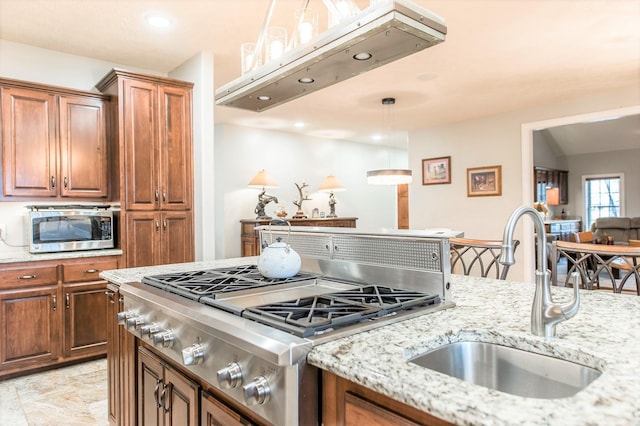 kitchen with light stone counters, sink, decorative light fixtures, and appliances with stainless steel finishes