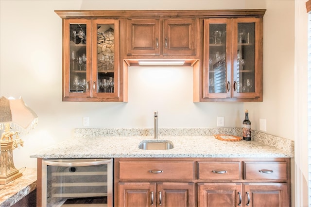 bar featuring light stone counters, beverage cooler, and sink