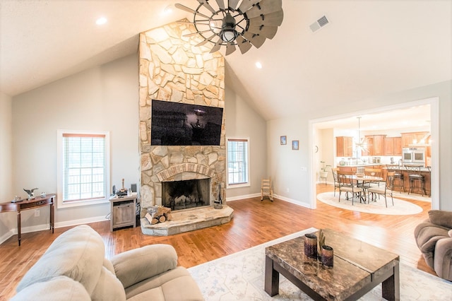 living room with ceiling fan, high vaulted ceiling, light wood-type flooring, and a fireplace