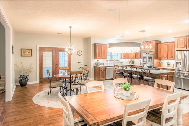 dining space featuring a chandelier, light wood-type flooring, and french doors