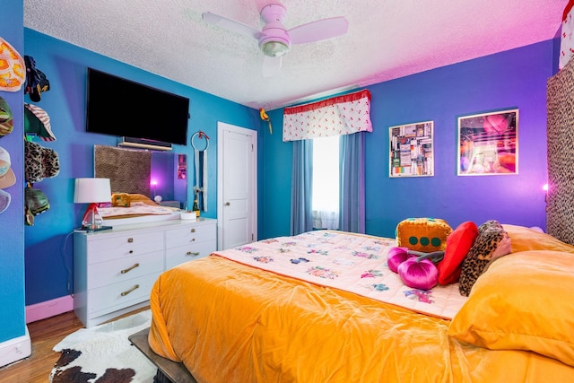 bedroom with ceiling fan, hardwood / wood-style flooring, and a textured ceiling