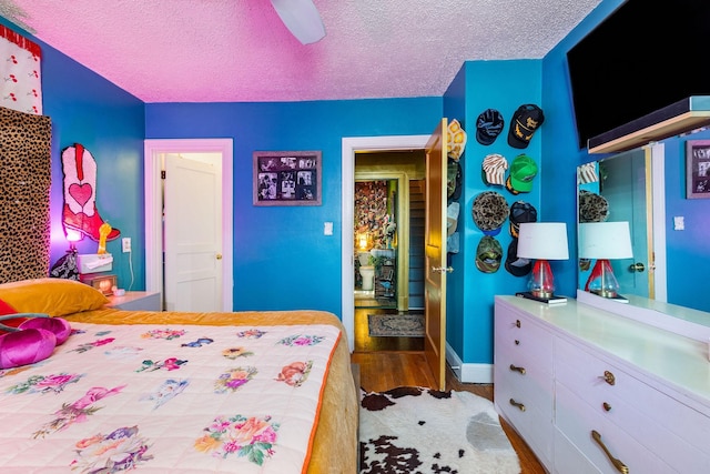 bedroom with ceiling fan, wood-type flooring, and a textured ceiling