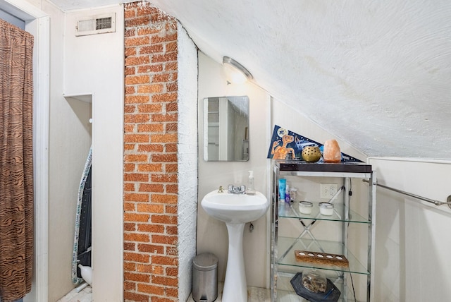 bathroom with vaulted ceiling and a textured ceiling