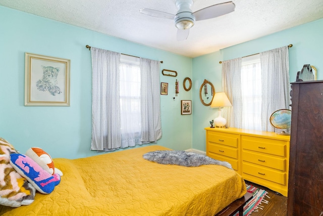 bedroom featuring multiple windows, ceiling fan, and a textured ceiling