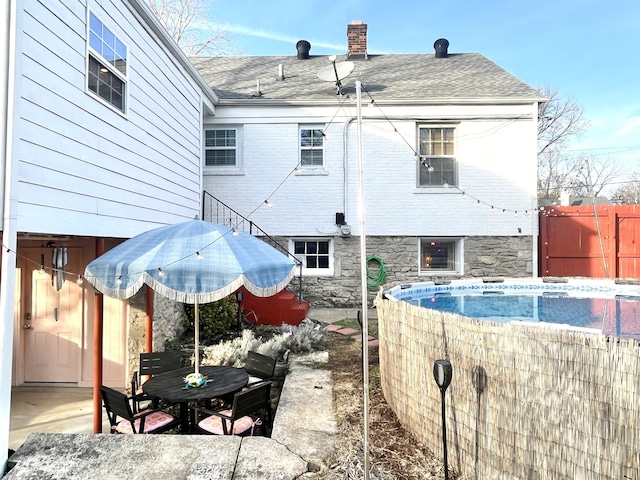 back of property featuring a fenced in pool and a patio area