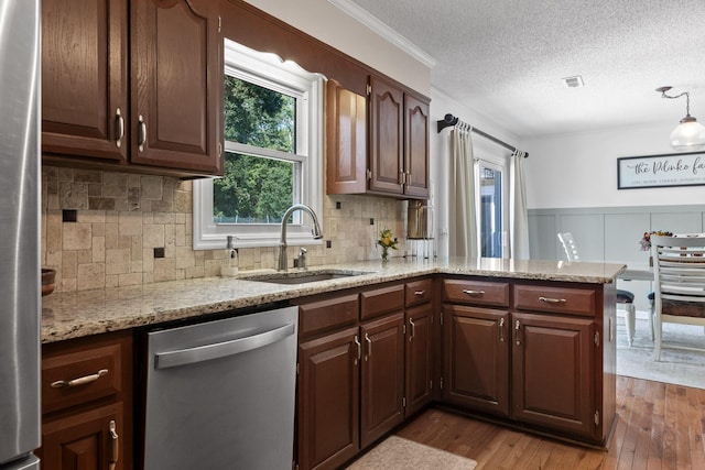 kitchen with sink, stainless steel appliances, light hardwood / wood-style floors, a textured ceiling, and kitchen peninsula