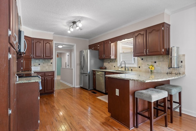 kitchen with stainless steel appliances, sink, decorative backsplash, and kitchen peninsula